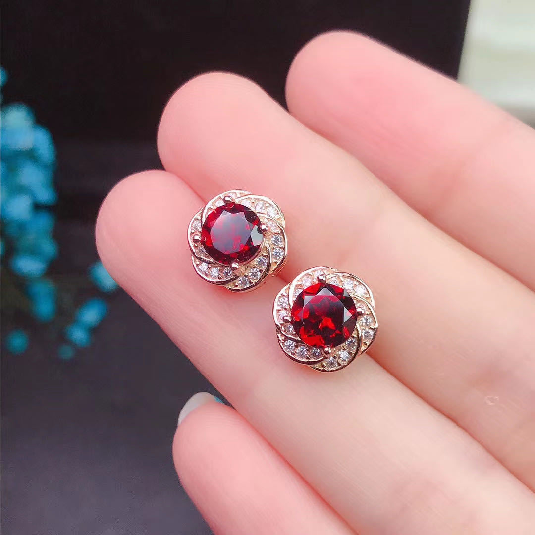 "Detailed view of hand-inlaid garnet on silver stud earrings"